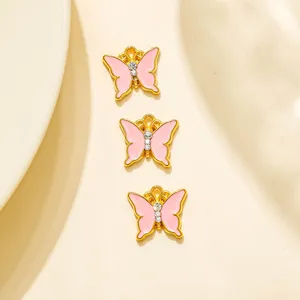 Gros plan de trois charms papillon en email rose bordes d or pour bijoux faits main.