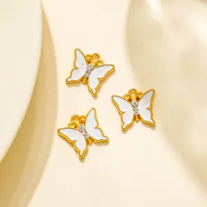 Gros plan de pendentifs papillon en émail blanc bordés d'or avec strass pour bijoux DIY.