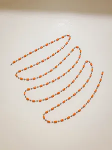 Close up detail of DIY orange tube bead and metal ball chain for handmade jewelry making.