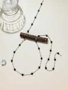 Gros plan sur les détails de la chaîne en acier inoxydable DIY avec perles blanches et noires.