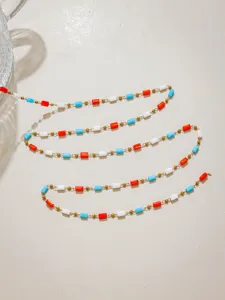 Detailed view of DIY beaded chain with gold balls and white, red, blue crystal tubes.