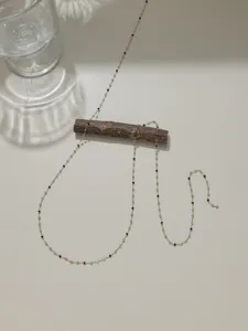 Gros plan détaillé sur la chaîne fine en acier inoxydable avec perles, accessoire chic.