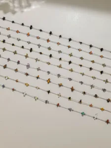 Close-up detail of natural gemstone chip beads on thin stainless steel chains for DIY jewelry.