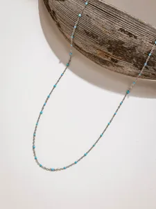 Detailed shot of delicate stainless steel chain necklace with tiny blue candy beads for DIY jewelry.
