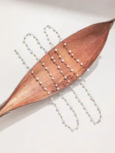 Nahaufnahme der filigranen DIY Perlenkette mit weißen Kristallen und goldenen Metallperlen.