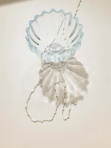 Close-up of delicate gold-toned DIY beaded chain with pearl and water-drop charms in glass.