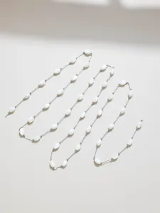 Close-up detail of white shell beads and metal chain for DIY jewelry making accessories