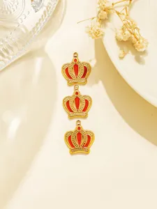 Close-up detail view of three golden crown pendants with red enamel, for DIY jewelry.