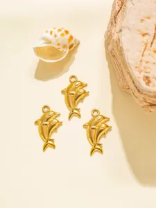 Primer plano detallado de tres colgantes de delfines dorados de acero, ideales para joyería DIY.