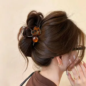 Nahaufnahme einer eleganten Schildpatt Herz Haarklammer im Dutt, ideal für schicke Alltagsdetails.
