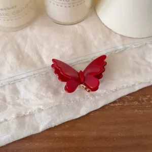 Nahaufnahme der glänzenden roten Schmetterlings-Haarklammer, die exquisite Textur zeigt.