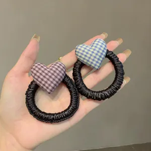 Detalle en primer plano de coleteros de corazón a cuadros estilo coreano, suaves de tela.