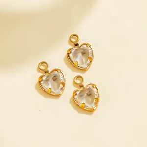 Close-up view of clear heart-shaped crystal charms with golden bezels for DIY jewelry making.