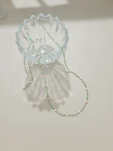 Detailed view of handmade crystal and pearl beaded chain, delicate jewelry making material showcase.
