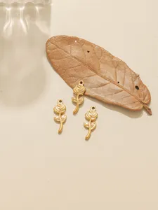 Close-up detail of golden rose flower pendant charms, perfect for DIY jewelry making.