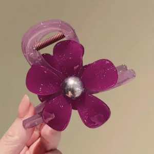 Detailopname van een paarse acetaat bloem haarclip met een zilveren kraal in.