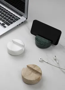 Detail shot of natural marble phone stand on clean white desk surface, minimalist design.
