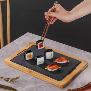 Rectangular black slate sushi plate set with bamboo wooden tray frame and chopsticks for food.