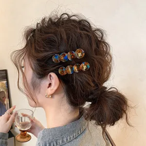 Acetat runde Haarklammer mit goldem B Logo, Seitenhaarspange für Damen, elegantes Accessoire.