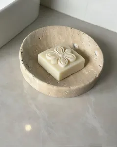 Close-up detail of natural marble soap dish with carved floral soap on stone countertop.