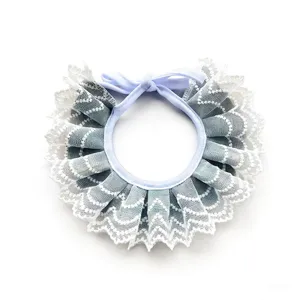 Close-up detail view of soft light blue lace pet bib featuring elegant bow and wave trim.