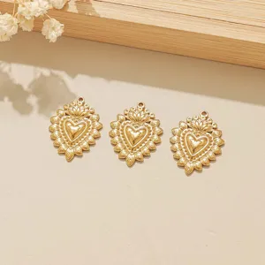 Vista dettagliata di tre ciondoli a cuore in acciaio inossidabile dorato per gioielli DIY.