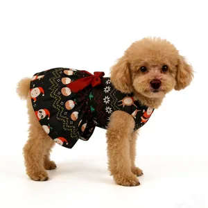 Close-up detail shot of the Christmas themed dog dress featuring cute holiday prints and a red bow.