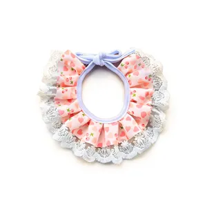 Closeup of cute pink lace pet bib with delicate cherry print and elegant white trim details.