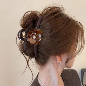 Vista dettagliata dell'elegante molletta per capelli marrone cioccolato con fiore di perla.