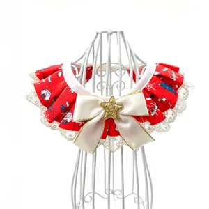 Détail bavoir de Noël pour animal, imprimé festif rouge, dentelle blanche et nœud avec étoile dorée.