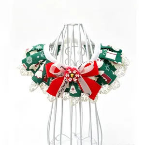 Détail bavoir col de Noël pour animal, tissu imprimé vert avec dentelle blanche et nœud.