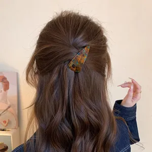 Detail shot of blue brown acetate triangular hair clip worn on back hair, stylish accessory.