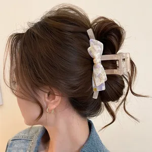 Dettaglio della molletta per capelli con fiocco in acetato, elegante accessorio.