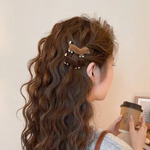 Close-up detail of cute velvet dachshund hair clips worn on wavy brown hair, stylish side clip.
