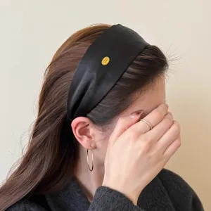 Nahaufnahme eines eleganten schwarzen Satin-Haarreifs am Model mit glatter Seidenoptik.