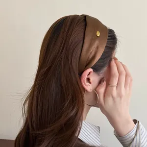 Nahaufnahme eines braunen Satin-Haarreifs im Haar, elegantes Seitenansicht-Accessoire.