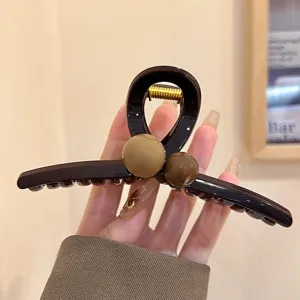 Detailansicht der eleganten braunen Haarklammer mit stilvollem Perlendesign für Frisuren.