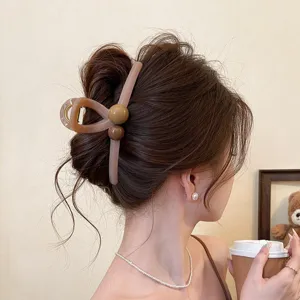 Detailansicht der eleganten braunen Haarklammer mit stilvollem Perlendesign und starkem Halt.