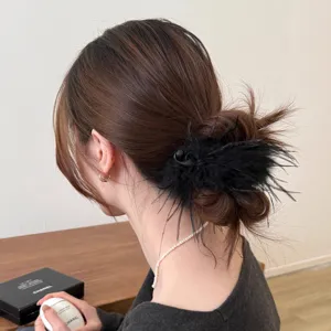 Detail shot of elegant black feather hair clip showcasing fine texture and stylish design.