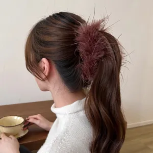 Elegant feather hair claw clip for women, fluffy high ponytail styling accessory detail.