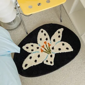 Black oval tufted floral rug with white spotted lily pattern, cozy bedroom bedside floor mat.