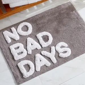 Detailansicht der weichen grauen Badematte mit erhabenem weißen NO BAD DAYS Schriftzug.