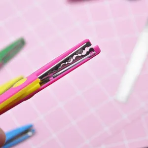 Close-up detail shot of pink and yellow decorative lace scissors for clay craft and DIY projects.