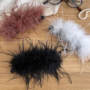 Close-up detail of fluffy feather hair clips in black, white, and brown, elegant banana clip design.