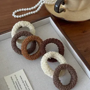 Detailed close-up of thick high-elasticity hair ties in neutral brown and white tones.