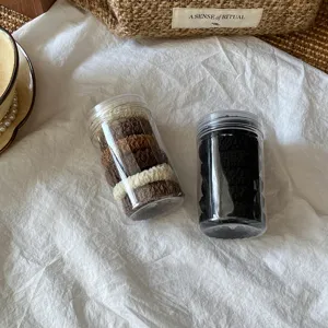 Detail shot of thickened high-elastic hair ties in transparent storage jars, minimalist daily wear.