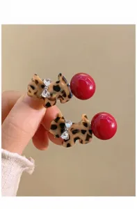 Close-up van schattige luipaardprint puppy haarspelden met sprankelende strass-steentjes en rode kralen.