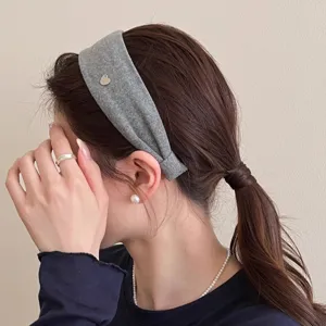 Nahaufnahme eines minimalistischen grauen breiten Haarreifs mit einem süßen Metallherz.