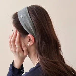 Nahaufnahme eines minimalistischen, breiten Stoff-Haarreifs mit edlem silbernen Herz-Anhänger.