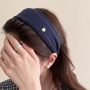 Nahaufnahme des dunkelblauen breiten Haarreifs mit einem süßen Herzanhänger am Kopf des Models.